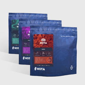 Three blue KOTA coffee bags on a white background