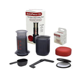 AeroPress Go coffee maker assembled with mug, paper filter, and red plunger